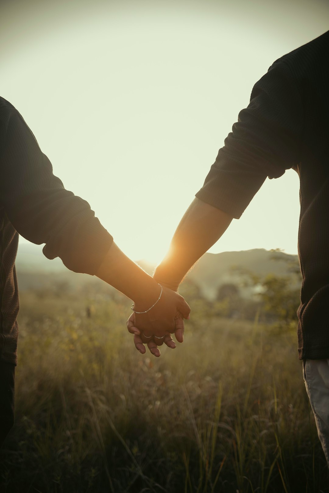 a-man-and-woman-holding-hands-in-a-field-heht8johglg